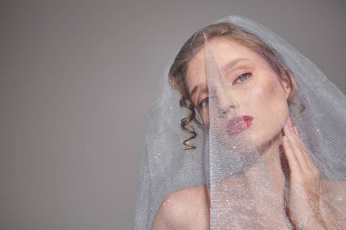 A young woman poses in a studio, wearing a veil on her head, exuding classic beauty and elegance. clipart
