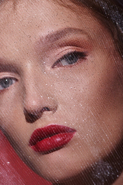 Молодая женщина с классической красотой, с красной помадой, соблазнительно смотрит на крупным планом фото на черном фоне.