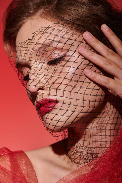 Молодая женщина излучает классическую красоту, позируя с вуалью, задрапированной над головой в студии..