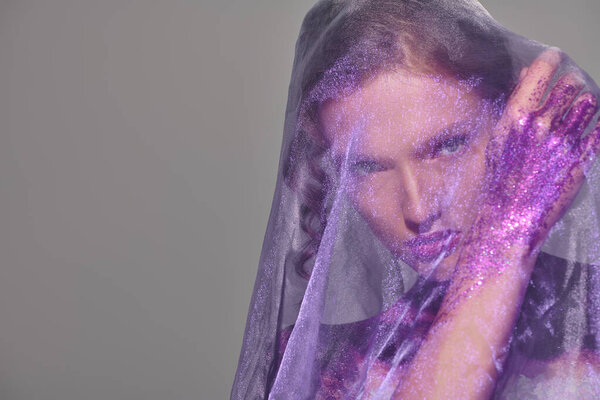 A classic beauty poses, her head adorned with a veil in shades of grey, exuding timeless elegance.