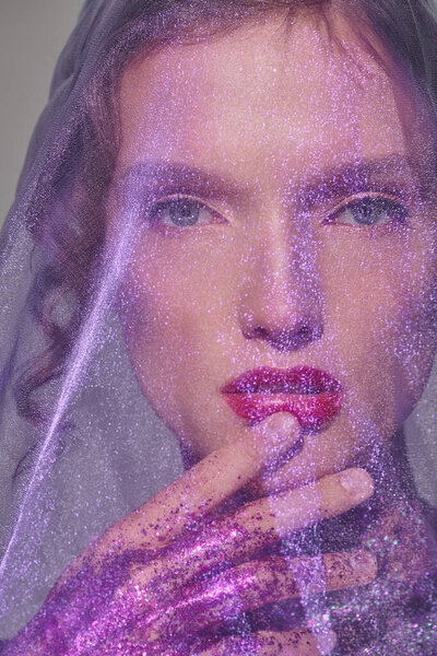 Молодая женщина излучает классическую красоту, когда она позирует с покрывалом на голове в спокойной обстановке студии.