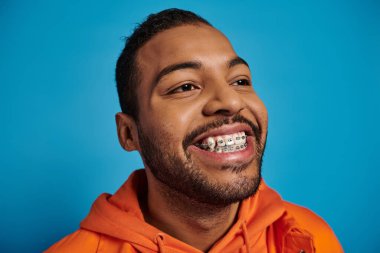 Mutlu ve çekici Afrikalı Amerikalı bir adam mavi arka planla yüzleşmek istiyor.