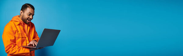 banner of happy african american young man in orange outfit enthusiastically playing in videogame