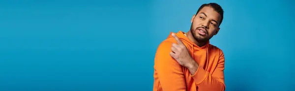 stock image banner of african american man in vibrant outfit looking to side and showing finger over shoulder