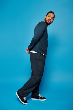 Çekici Afro-Amerikalı siyah elbiseli adam ellerini kavuşturup arkasını kolluyor.