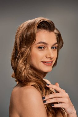 Uzun dalgalı saçlı genç, güzel bir kadın çarpıcı bir portre için zarafet ve zarafet saçar..