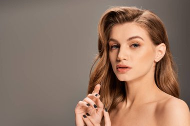 Uzun dalgalı saçlı genç bir kadın gizemli ve büyüleyici bir aura yayıyor..