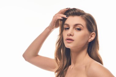 Uzun, dalgalı saçları olan çekici genç bir kadın kameraya büyüleyici bir poz veriyor..