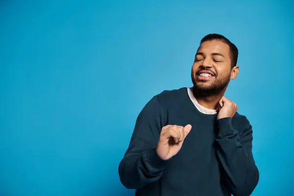 stock image happy african american man in his 20s dancing with closed eyes against blue background