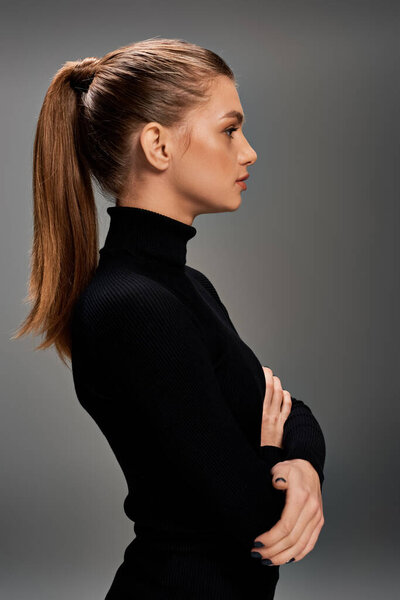 Молодая красивая женщина с длинными волнистыми волосами элегантно оформленная в хвосте, в шикарной черной водолазке.