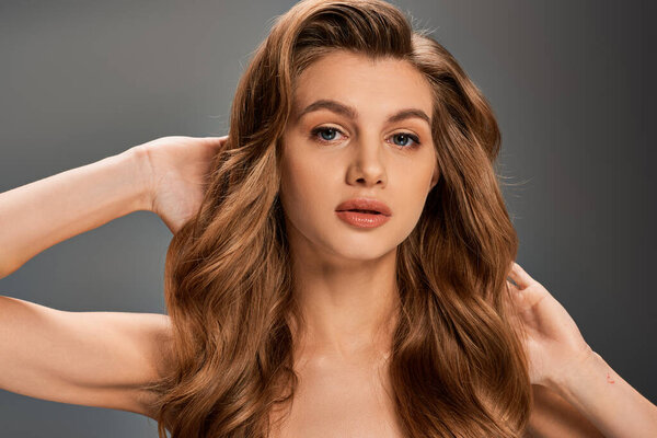 Молодая женщина с потрясающими длинными волнистыми волосами, изящно позирующая перед камерой.