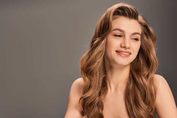 Молодая красивая женщина с длинными волнистыми волосами, ставящая перед камерой позу, источая уверенность и элегантность.