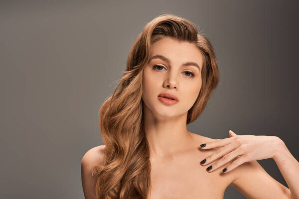 Молодая красивая женщина с длинными волнистыми волосами, позирующая для портрета.