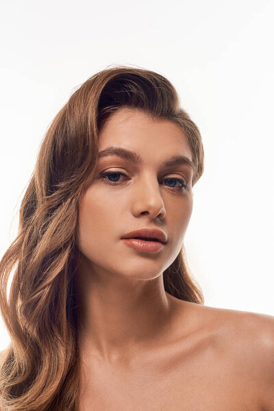 Молодая, красивая женщина с длинными волнистыми волосами элегантно оформлена, излучая уверенность и изящество.