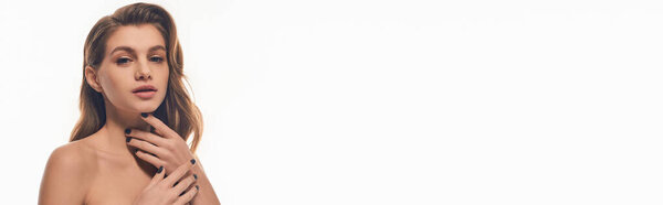 A young woman with long wavy hair, gently places her hands on her chest.