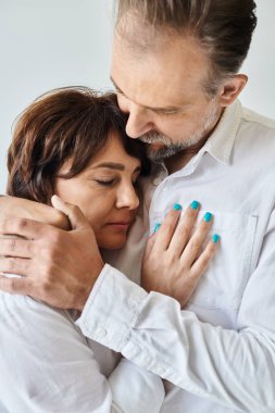 Çekici orta yaşlı kadın beyaz gömlekli olgun bir adama sarılıyor.