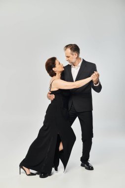 Full length shot of mature attractive couple in a tango dance pose isolated on grey background clipart