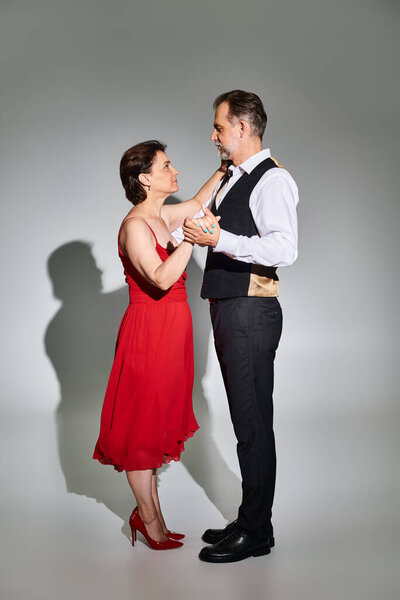 Бальные танцы средних лет пара в красном платье и костюме танго танго изолированы на сером фоне