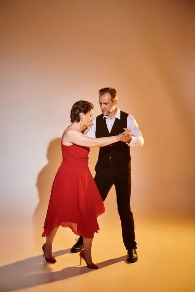 stock image Ballroom dance middle aged couple in red dress and suit dancing tango isolated on grey background