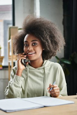 Farklı geçmişlerden bir kadın ortak çalışma alanında cep telefonuyla konuşuyor..