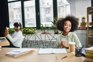 Masada oturan bir kadın, rahat bir ortamda bir fincan kahvenin tadını çıkarıyor..