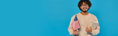 Sıradan giyinmiş bir adam arka planında Amerikan bayrağı olan bir pano tutuyor. Vatanseverlik ve organizasyonu gösteriyor..