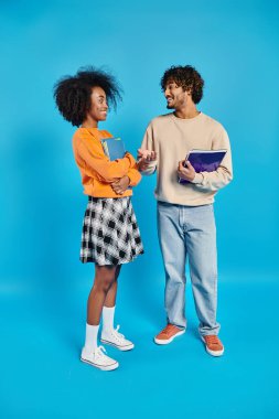 An interracial couple standing united in casual attire against a vibrant blue backdrop. clipart