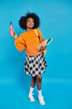 An African American college girl standing with a book in one hand and an American flag in the other, exuding patriotism. clipart