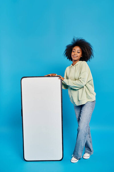 A woman confidently stands next to a massive white board, ready to share ideas and inspire creativity.