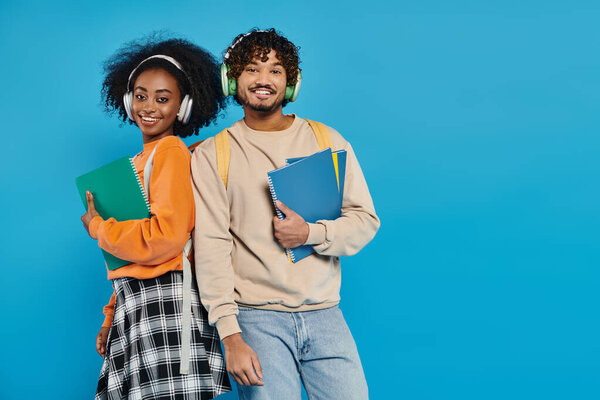 A man and a woman of different races standing together in casual attire, showcasing unity and diversity in a studio setting.