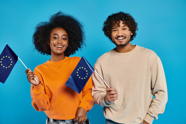 A man and a woman, an interracial couple, proudly holding two flags together in a show of unity and harmony.