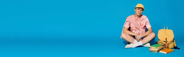Стильный Молодой Человек Сидит Рядом Рюкзаком Синем Фоне Олицетворяя Чувство — стоковое фото