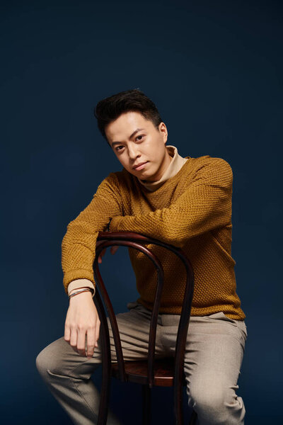 A fashionable young man in elegant attire defying gravity as he balances skillfully on top of a wooden chair.