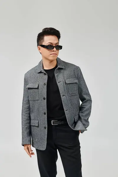 Модный Молодой Человек Занимает Уверенную Позу Серой Куртке Черных Штанах — стоковое фото