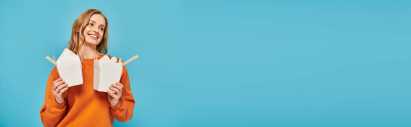 Женщина прячется за двумя коробками с едой перед лицом