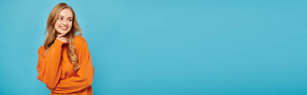 Потрясающая женщина с светлыми волосами, ставящая позу на синем фоне.