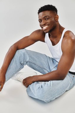 Genç bir Afro-Amerikan adam bacaklarını çapraz oturarak serin bir pozisyonda oturuyor..