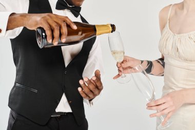 Smokinli sofistike bir adam bardağa şampanya dolduruyor. Kutlama ve kibarlık atmosferi yaratıyor..