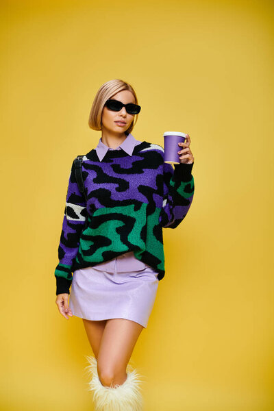 attractive cheerful woman with stylish sunglasses in vibrant attire posing with coffee cup in hand