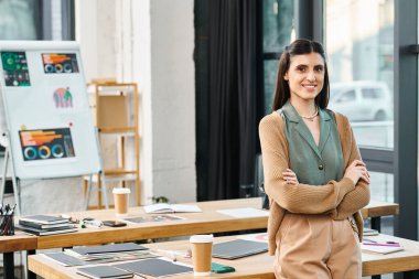 A woman stands confidently in front of a table in a corporate office setting, embodying leadership and creativity. clipart