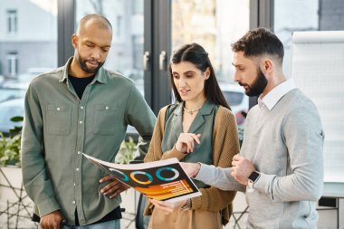 Çeşitli profesyonellerden oluşan bir grup ofis ortamındaki bir iş dergisinin içeriğini tartışıyor..