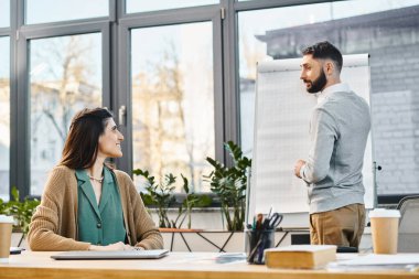 Modern ofis ortamında bir kadın ve erkek, bir proje hakkında konuşmaya daldılar..