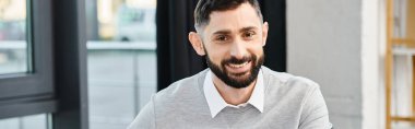 Beyaz gömlekli sakallı bir adam, kurumsal ofis ortamında bilgelik ve deneyim yayar..