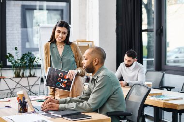 Bir erkek ve bir kadın, projelerine dalmış şık bir ofis masasında odaklanmış bir tartışmaya girişiyor..