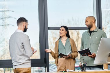 Çeşitli profesyonellerden oluşan bir grup, bir ofis ortamında dizüstü bilgisayarın etrafında toplanıp, ortak bir proje tartışması yapıyorlar..