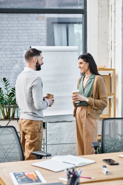 Bir adam ve bir kadın beyaz tahtanın önünde duruyor, modern ofis ortamında bir proje için beyin fırtınası yapıyorlar..