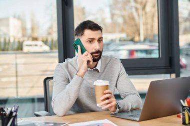 İş ortamında bir adam, masada oturuyor, bir telefon görüşmesi yapıyor..