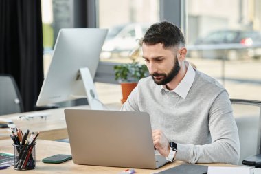 A man immersed in work, sitting at a desk, typing on a laptop in a bustling office environment. clipart