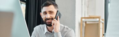 Şirket kıyafetli bir adam masada oturuyor, cep telefonuyla konuşuyor..