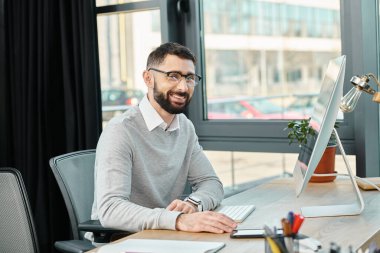 Bir adam masasına odaklanmış şirket ofisindeki bir bilgisayar üzerinde çalışıyor..